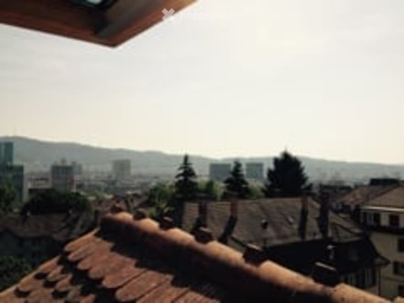 Balcony with a view of a cityscape, including rooftops, buildings, and distant hills.