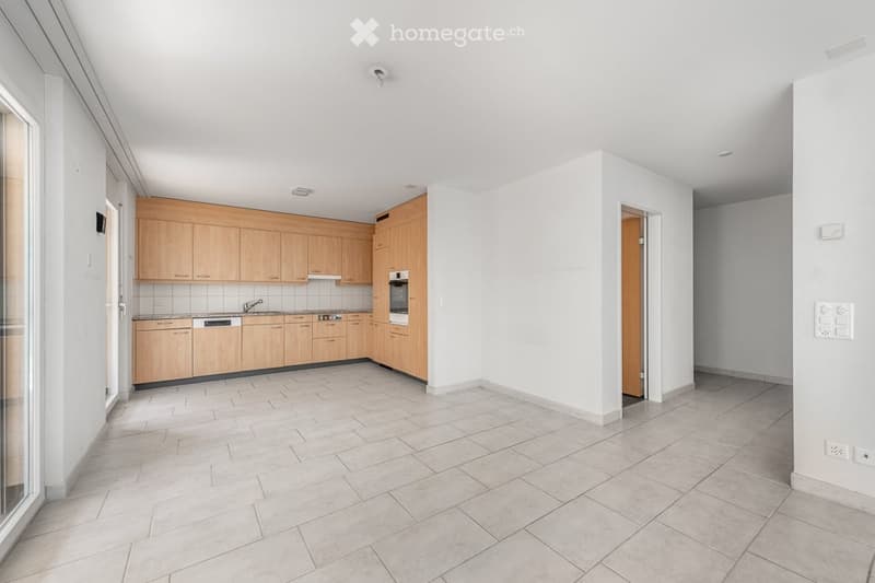 Modern kitchen with light wooden cabinets, stainless steel appliances, and tiled flooring.