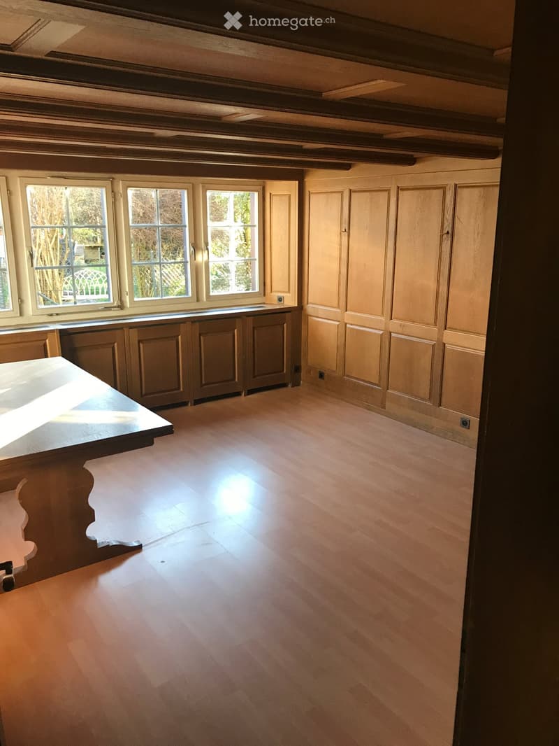 Empty room with wooden flooring, built-in cabinets, and large windows allowing natural light to enter.