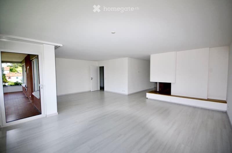 open room with floor, fireplace in corner, balcony at end