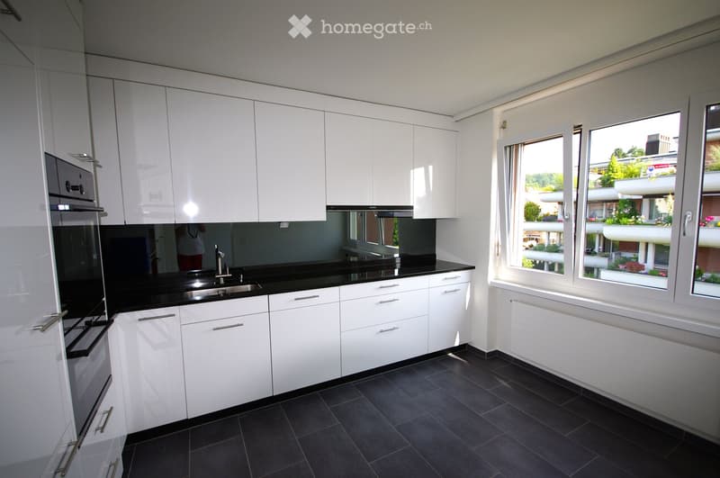 modern kitchen, white cabinetry, black countertops, stainless steel appliances, window