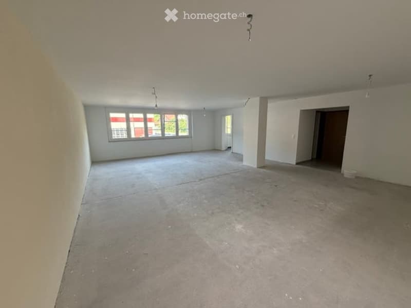Empty room with bare walls and concrete floor, large windows, no furniture or equipment.