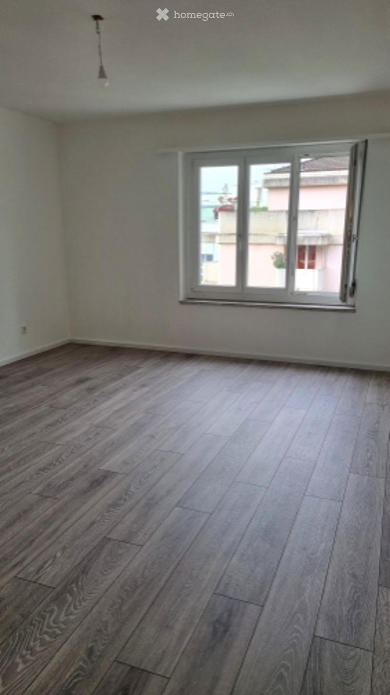 room with wooden flooring, white walls, large window, empty room