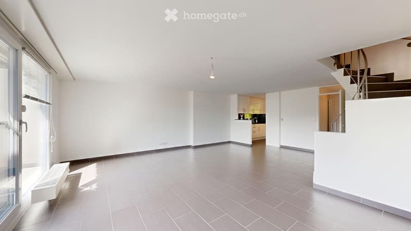 Completely empty room with white walls, grey tiled floor, and large windows. No furniture or equipment.