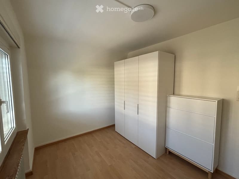 Empty room with light-colored walls, wooden flooring, and white built-in wardrobes.