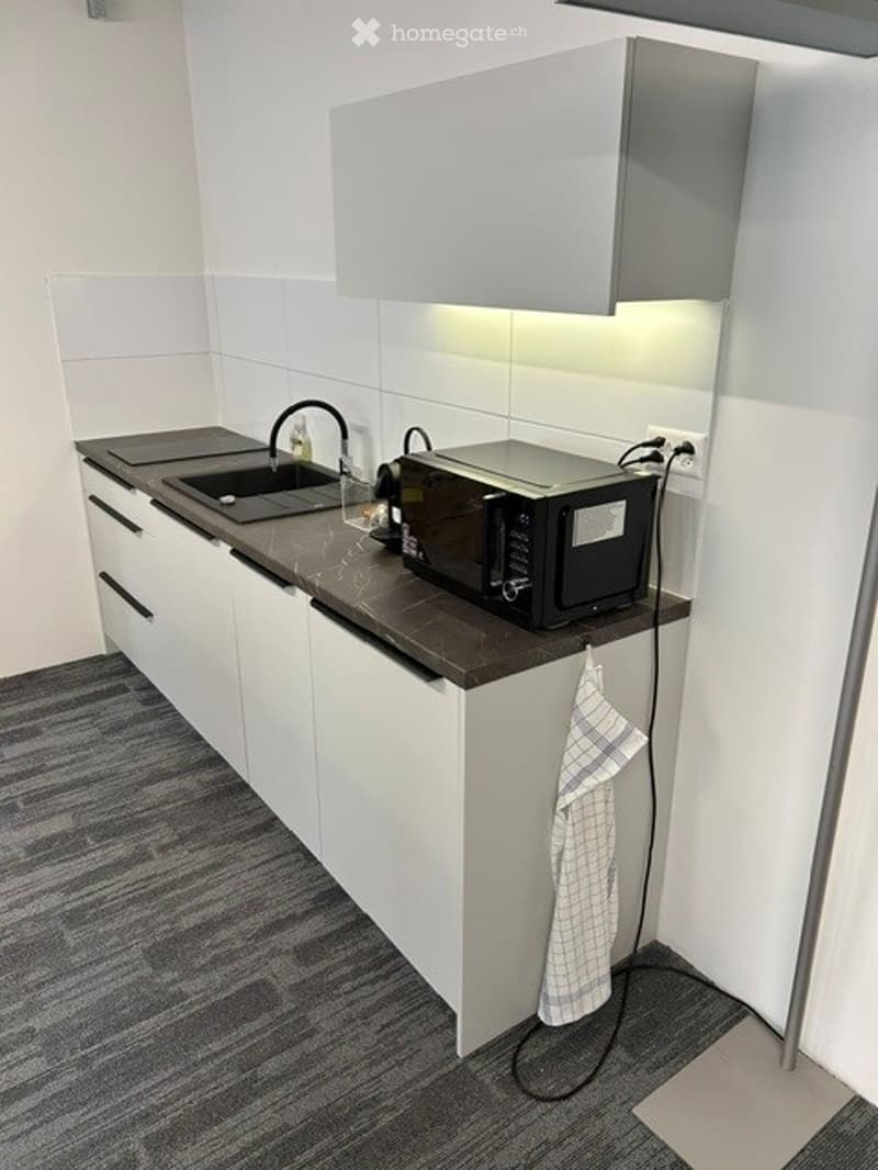 Modern kitchen with white cabinets, dark countertop, sink, faucet, microwave, and a towel hanging from a hook.