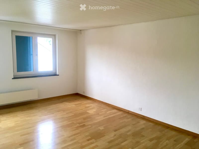 Empty room with wooden flooring, white walls, and a single window with blinds.