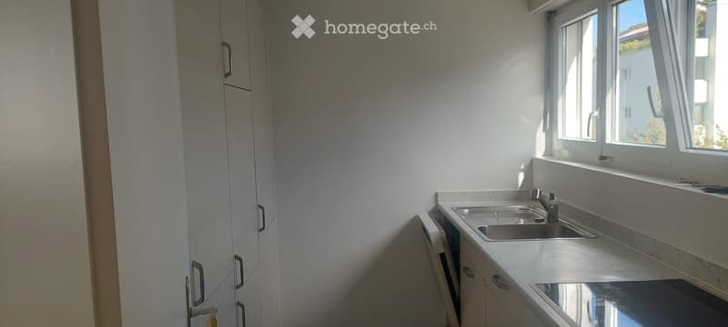 Modern kitchen with white cabinets, marble countertop, and stainless steel sink.