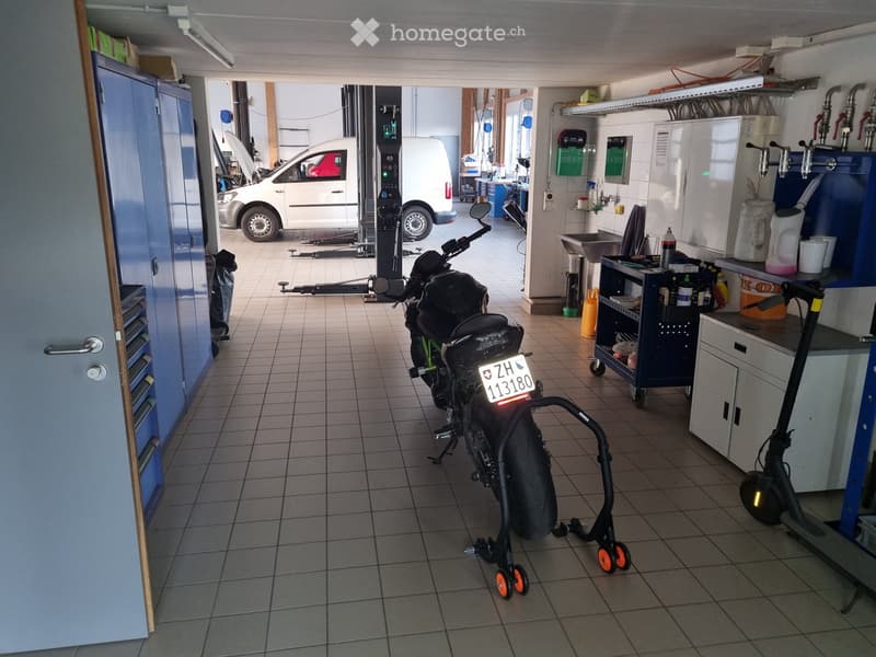 Other. Garage with tiled floor, containing a motorcycle on a stand, a scooter, a van, tool cabinets, workbench, and a sink area with a faucet.