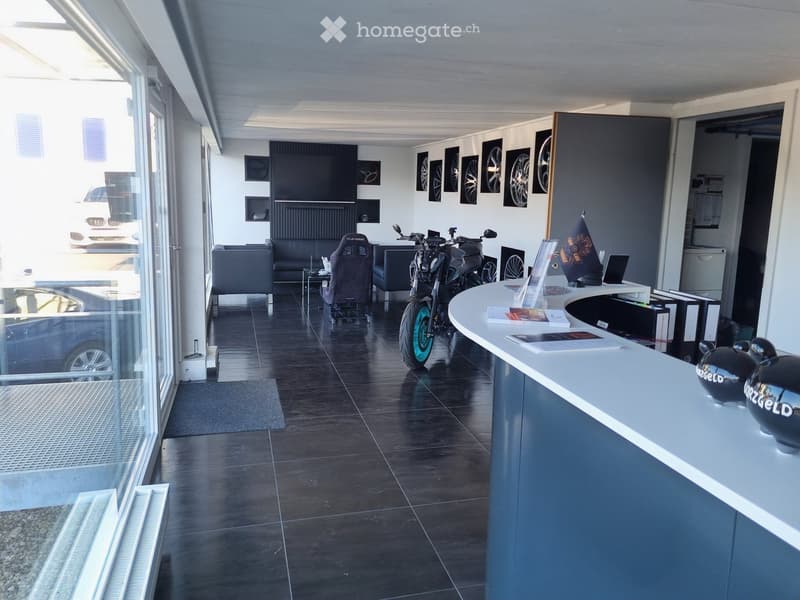 Furnished Room. Modern reception area with dark tiled floor, white reception desk, sofa, chairs, motorcycle, and framed pictures on the wall.