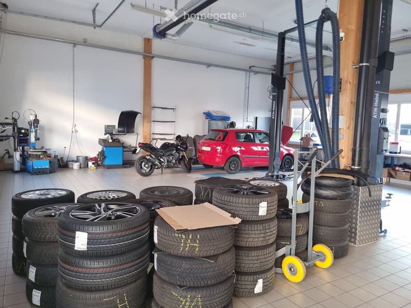 Other. Garage with a red car on a lift, a motorcycle, stacks of tires, and various workshop equipment.