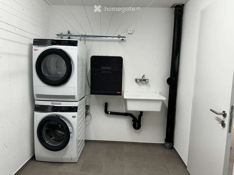 Modern bathroom with a stacked washer and dryer, a small sink, and a faucet.