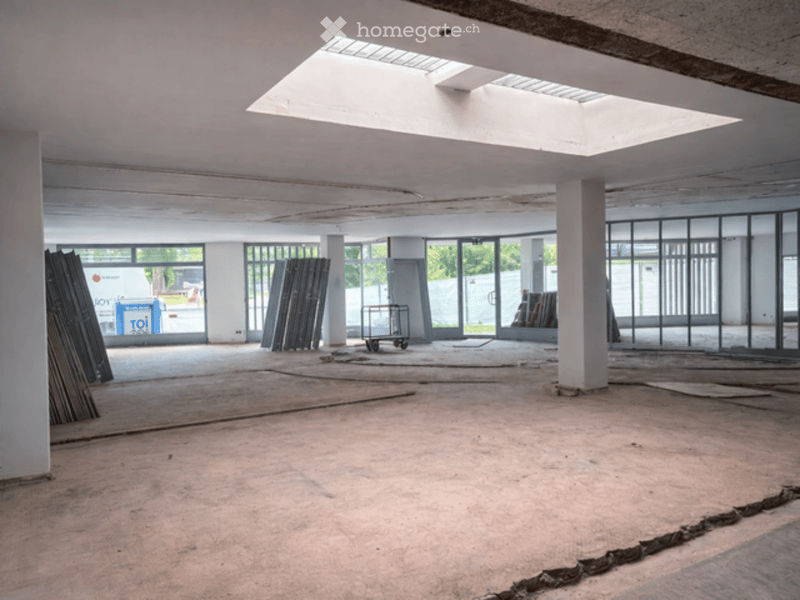 Empty room with bare walls, concrete floor, and large windows. No furniture or equipment present.