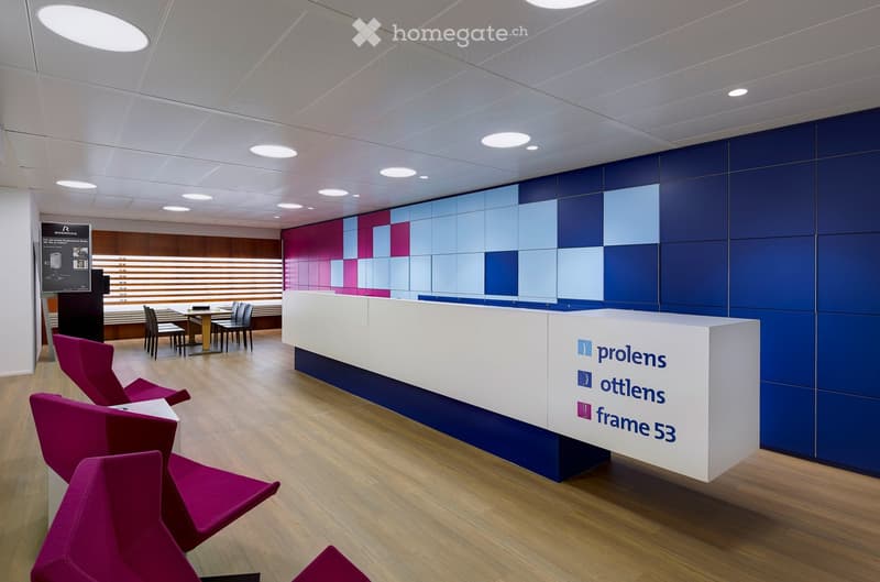 Modern reception area with a white reception desk, purple chairs, and a small meeting table with chairs in the background.