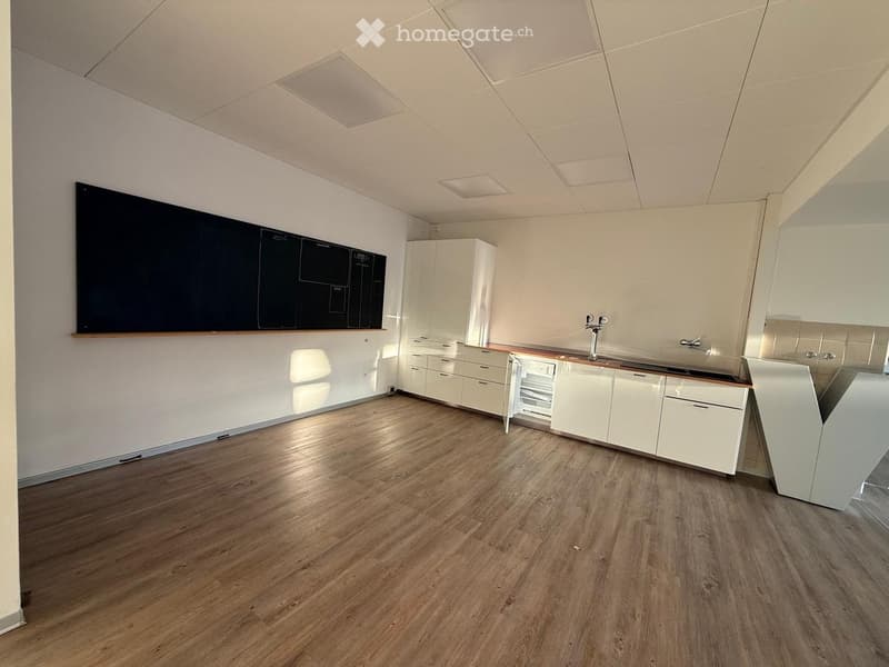 Modern kitchen with white cabinets, wooden flooring, and a large blackboard on the wall.