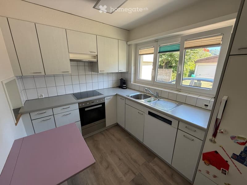Modern kitchen with white cabinets, stainless steel appliances, and a double sink. Features include a built-in oven, dishwasher, and a coffee maker on the counter.