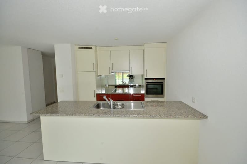 Modern kitchen with white cabinets, granite countertop, stainless steel sink, and built-in oven.