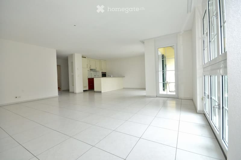 Empty room with white tiled flooring, white walls, and a doorway leading to another area. The space is clean and unfurnished.