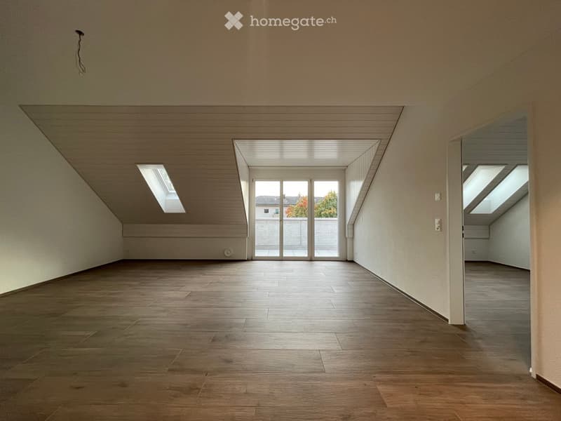 Empty room with wooden flooring, white walls, and skylights providing natural light. No furniture or equipment present.