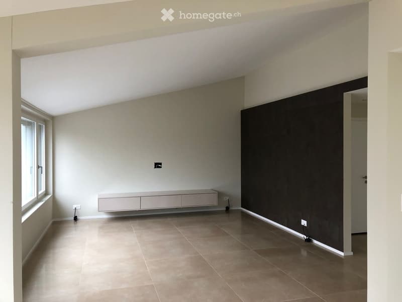 Empty room with beige tiled floor, white walls, and a built-in cabinet under a window. No furniture or equipment present.