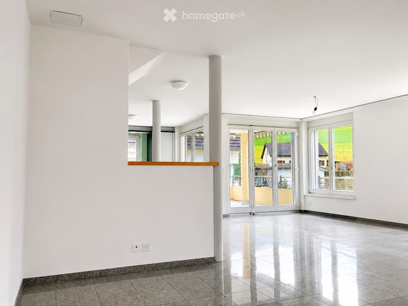 Empty room with white walls, polished tile floor, large windows, and sliding glass doors leading to an outdoor area.