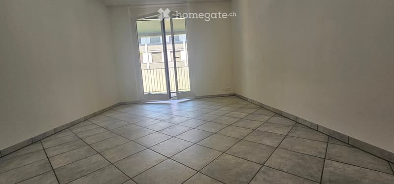 Empty room with tiled floor and large sliding glass door leading to a balcony.