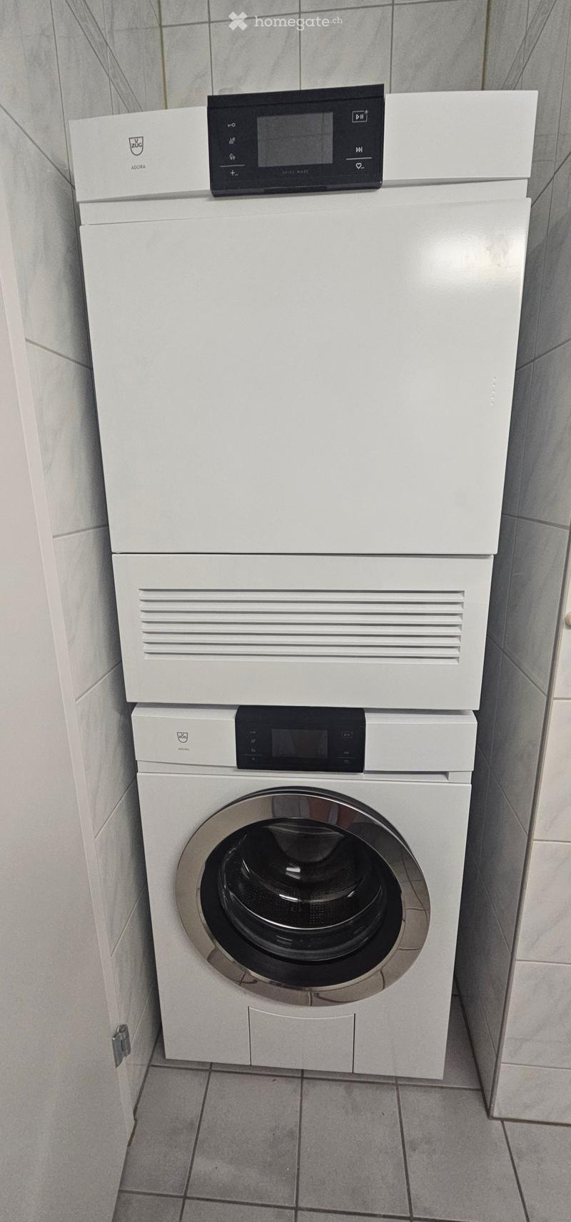 A modern bathroom with a white washing machine and a white dishwasher stacked vertically, featuring sleek control panels.