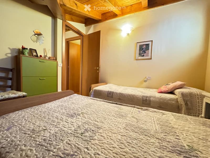 Cozy bedroom with two single beds, a green cabinet, a mirror, and a picture frame on the wall.