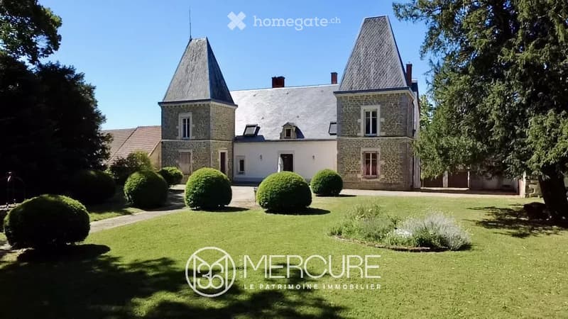 A large, elegant stone manor house with a grey slate roof, multiple chimneys, and symmetrical design, surrounded by a well-maintained lawn and manicured hedges.