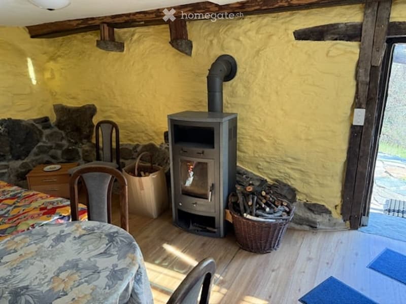 Cozy room with wooden floor, yellow walls, wood stove, sofa, table, and chairs.