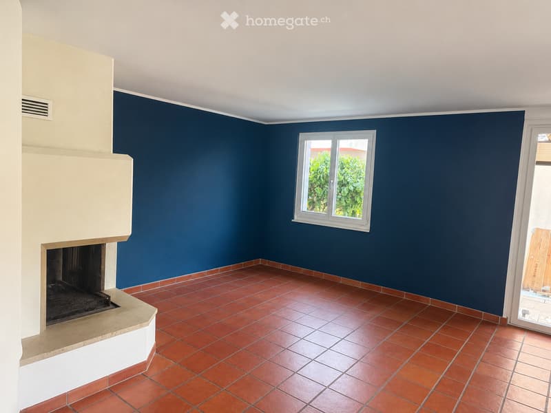 Unfurnished Room. Empty room with red tiled floor, dark blue walls, fireplace, and a window with a view of greenery.