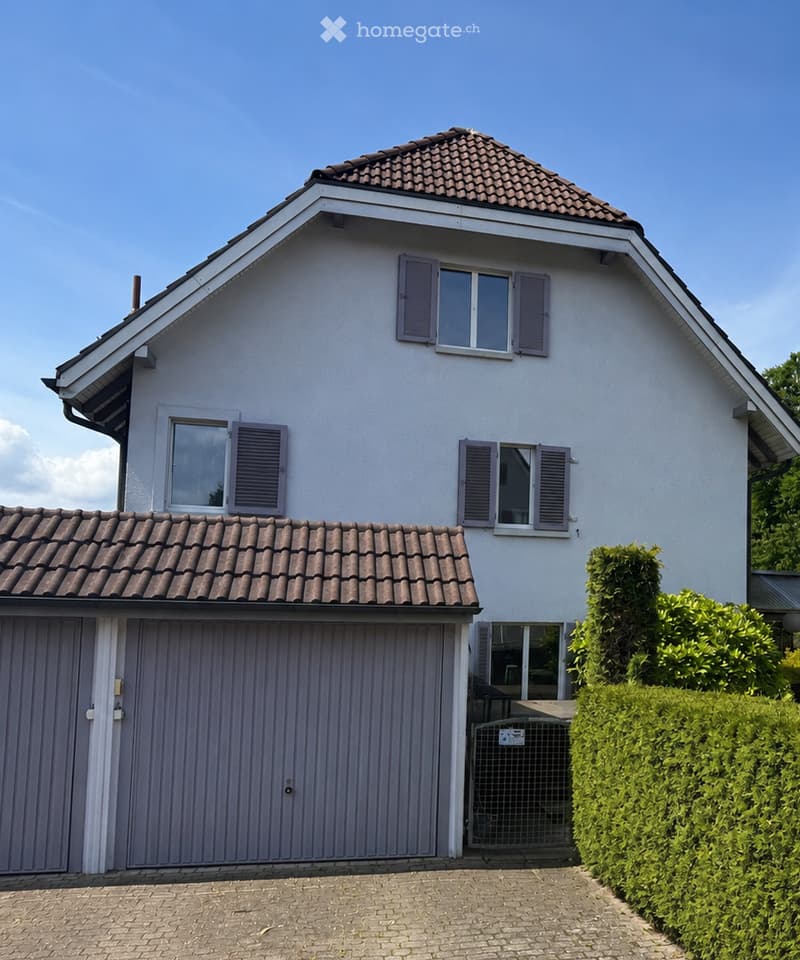 House. Two-story house with white exterior, brown tiled roof, multiple windows with shutters, and a garage.