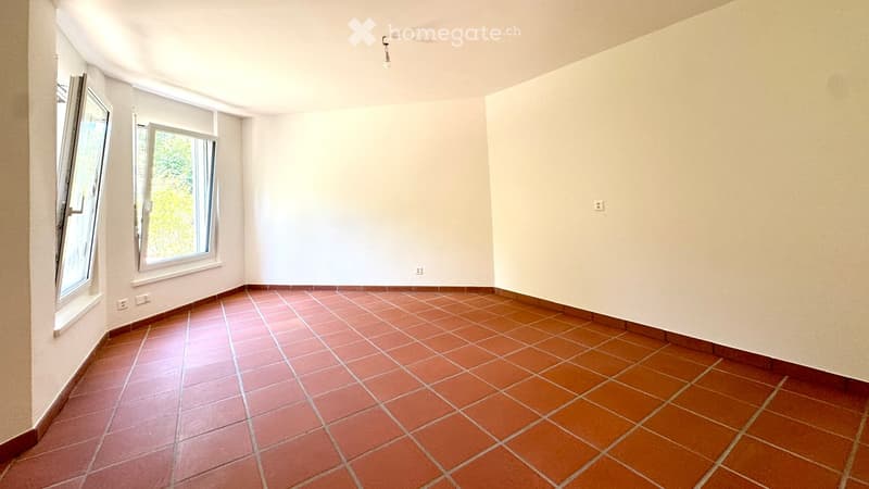 Empty room with tiled floor and white walls, featuring two large windows with open shutters allowing natural light.