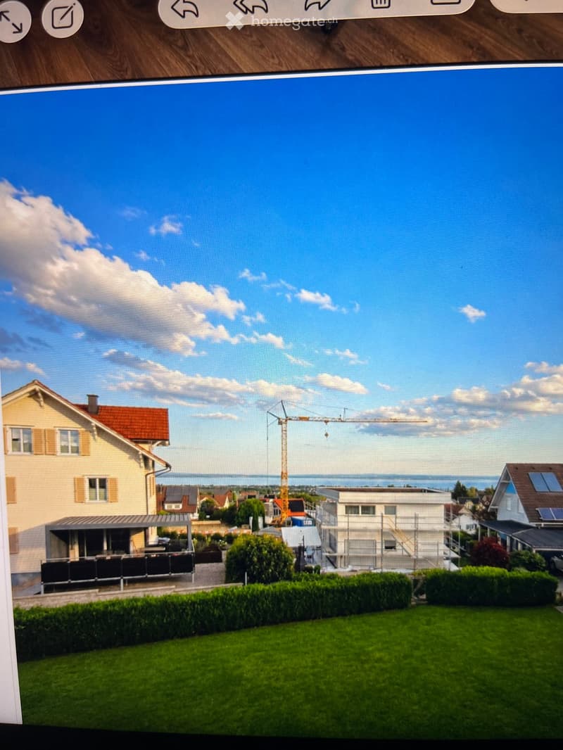 A digital rendering of a suburban neighborhood with a well-maintained lawn, a covered patio area, and several houses under construction, including a prominent crane in the background.