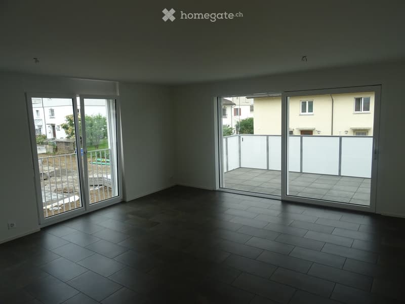 Empty room with tiled floor, large sliding glass doors leading to a balcony and outdoor area.