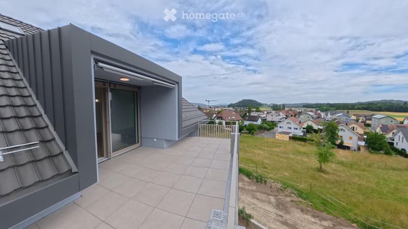 Modern balcony with tiled floor, glass sliding door, metal railing, and scenic view of a suburban neighborhood.