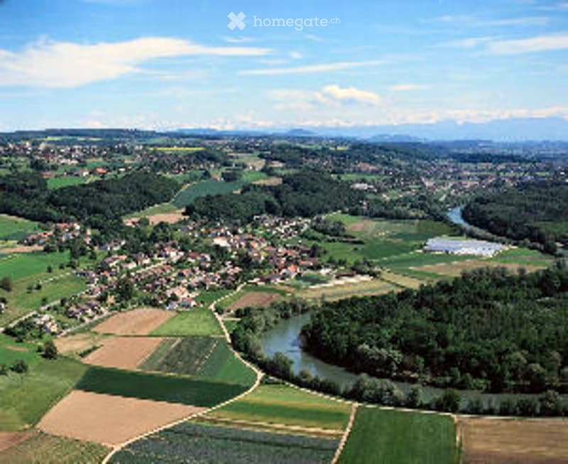 Aerial view of a rural area with scattered houses, agricultural fields, and a winding river surrounded by trees.