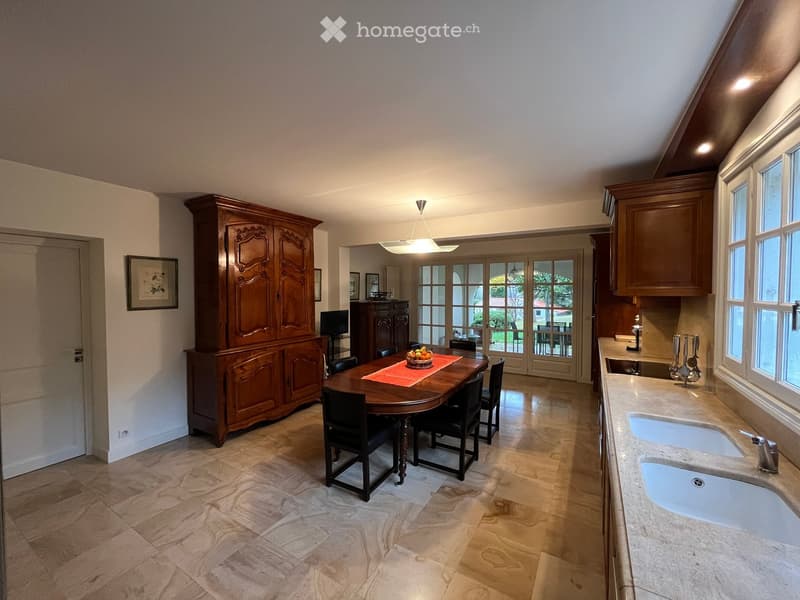 large wooden cabinet, dining table with 6 chairs, chandelier, kitchen with double sink, open doors