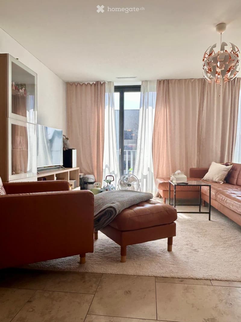 Modern living room with a large window and balcony access, featuring a leather sofa, ottoman, coffee table, fan, television, and cabinet.