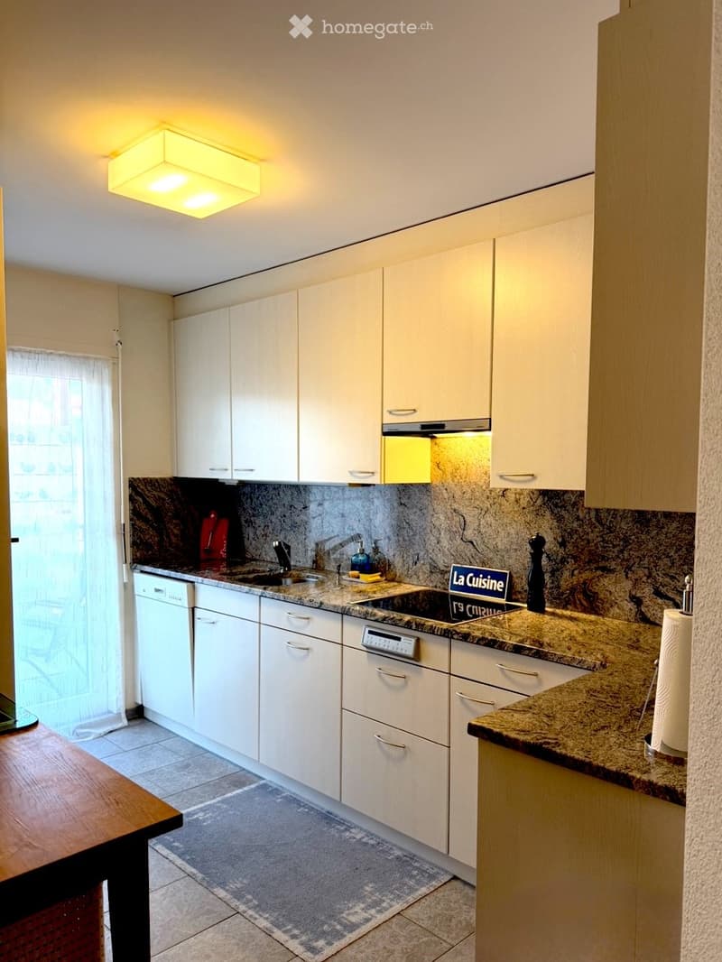 Modern kitchen with white cabinets, granite countertops, and stainless steel appliances, including a dishwasher and sink.