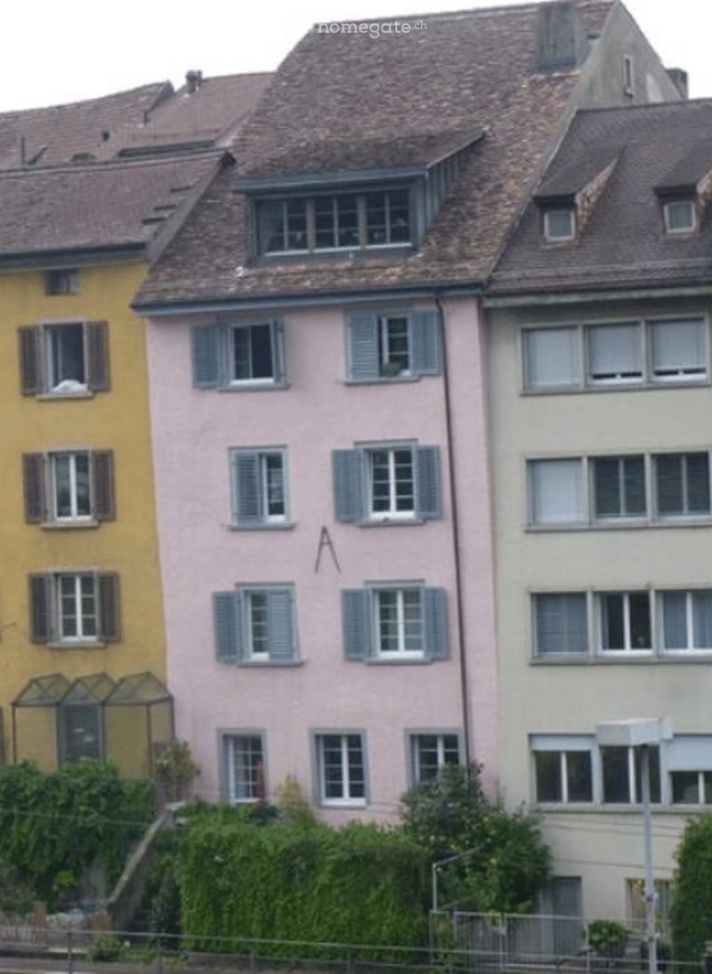 A row of three multi-story residential buildings with distinct facades, featuring multiple windows with shutters and tiled roofs.