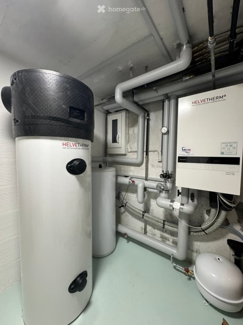 Utility room with a water heater, control panel, and various pipes.