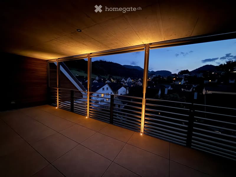 modern terrace with tiled floor and metal railings, night view of a town, yellow lighting