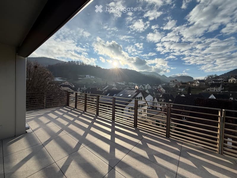 large balcony, wooden railing, open view of town, mountains, sunny day