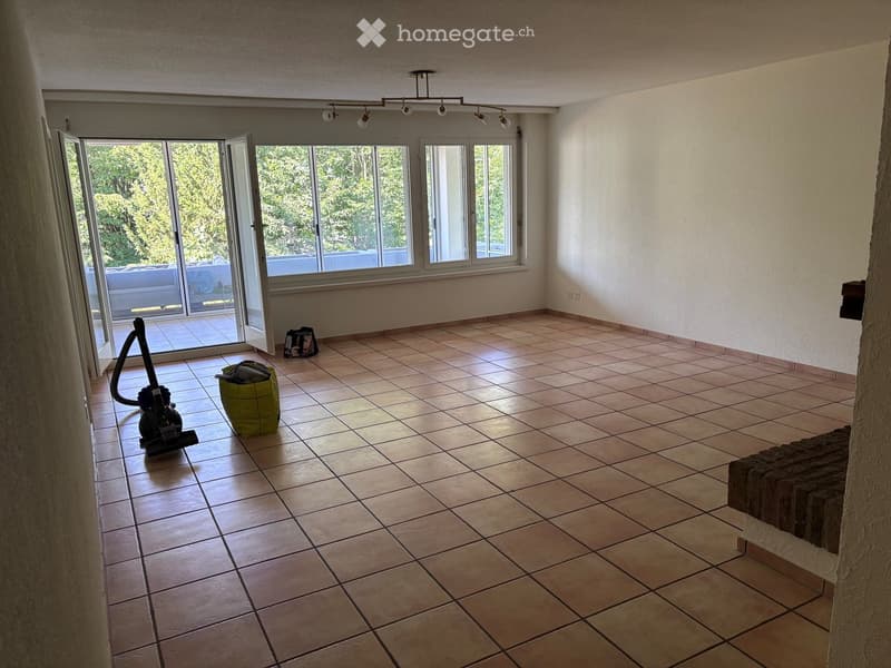 Empty room with tiled floor, large windows, and sliding glass doors leading to an outdoor area.