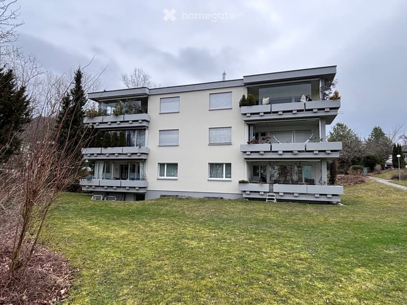 Modern two-story house with multiple balconies, large windows, and a well-maintained lawn in front.