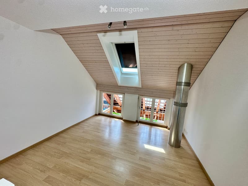 Empty hallway with wooden flooring, white walls, and a skylight window at the far end. A metal pipe is visible on the right side.
