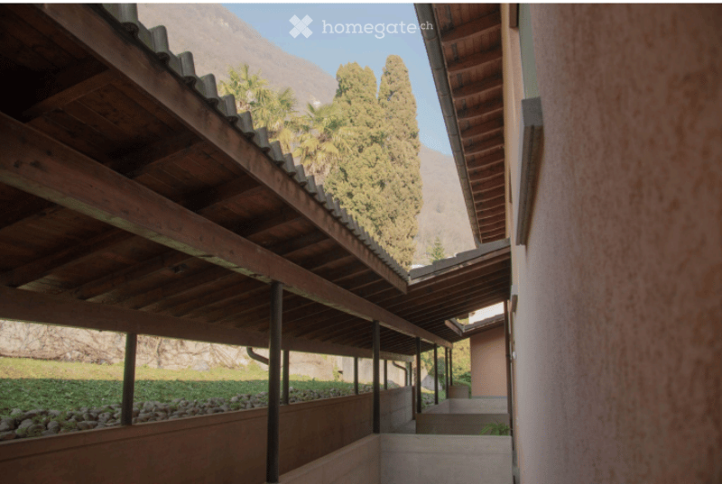 Wooden balcony with open sides, overlooking a scenic view of trees and mountains.