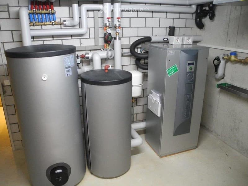 Utility room with water heater, boiler, and various pipes and valves.