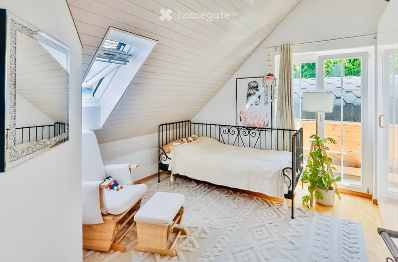 small bedroom with bed, chair, ottoman, rug, mirror, potted plant, glass door